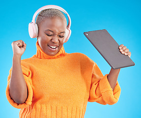 Image showing Winner, success or black woman in studio with tablet, achievement or bonus on blue background. Headphones, giveaway or happy person with technology in celebration of reward, prize or online victory