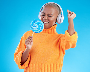 Image showing Music headphones, lollipop or black woman listening to radio playlist to relax on blue background in studio. Sweets, candy or girl singer dancing, singing or streaming a song audio or sound track