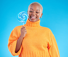 Image showing Smile, lollipop and black woman with candy in studio isolated on a blue background. African person, happy and tongue out for sweets, dessert and treats, sugar food and confectionary for eating