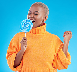 Image showing Singing, lollipop and a woman with candy in studio for sweets, rainbow and creative advertising. Happy black female person isolated on a blue background with sugar, freedom and happiness or color