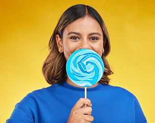 Image showing Lollipop, candy and portrait of woman with sweet dessert with sugar isolated in a studio yellow background with smile. Food, snack and young person with delicious treats, product or guilty pleasure