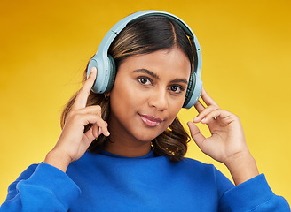 Image showing Headphones, portrait and young woman in a studio listening to music, playlist or album with confidence. Happy, smile and headshot of female model streaming song or radio isolated by yellow background