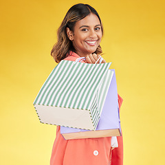 Image showing Portrait, woman and smile with shopping bag in studio for fashion, retail deal or financial freedom on yellow background. Indian customer, gift bags and discount at boutique, store or sales promotion