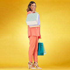 Image showing Portrait, happy woman and shopping bag in studio for clothes, retail deal and financial freedom on yellow background. Indian customer, gift bags and discount from fashion store, sales and promotion