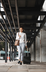Image showing Phone, travel and luggage with a business woman in an airport parking lot walking outdoor in the city. Mobile, suitcase and commute with a young corporate employee on an international trip for work