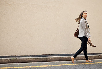 Image showing Woman in street, walking at wall with mockup and barefoot, relax and travel for work holiday in city. Space, road and freedom, person on walk with shoes in hands, morning commute and business trip.