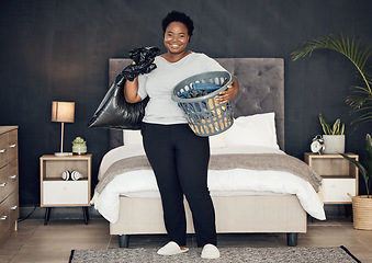 Image showing Black woman, clothes in basket and cleaning bedroom, garbage bag and hygiene with portrait in bedroom. Female person, cleaner and housekeeping with smile, laundry and maintenance with morning routine