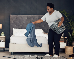 Image showing Black woman, clothes with basket and cleaning bedroom, organize mess with hygiene and hospitality. Female person, cleaner and housekeeping, busy with laundry and maintenance with morning routine
