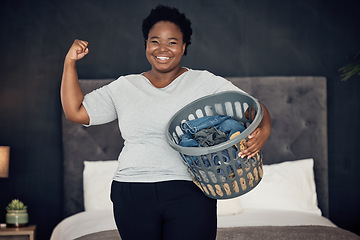 Image showing Black woman, clothes in basket and champion, success in cleaning and bedroom with hygiene in portrait. Strong female cleaner, winner at housekeeping with smile, laundry and maintenance at home