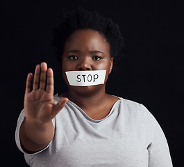 Image showing Portrait, stop and palm with a black woman in studio on a black background for gender equality or domestic violence. Hand, silence or abuse and a scared female victim with her mouth covered in fear