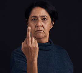 Image showing Portrait, anger and senior woman with middle finger, opinion and expression on a black studio background. Face, female person and old model with gesture, rude and frustrated with problem and conflict