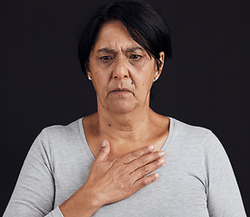 Image showing Fear, senior and a woman with a heart attack on a black background with healthcare anxiety. Emergency, sad and an elderly person feeling chest for pain, sick or medical scare isolated on a backdrop