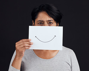 Image showing Portrait, fake smile or depression and a mature woman in studio on a dark background with an expression. Abuse, anxiety and mental health with a female person looking brave to hide her emotions