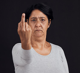 Image showing Portrait, reject and senior woman with middle finger, opinion and angry expression on a black studio background. Face, female person or elderly model with hand gesture, rude and frustrated with anger