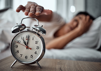 Image showing Alarm, morning and a hand with a clock for awake, oversleep or tired in the bedroom of a home. House, ring and a closeup of a person or woman in bed for snooze, rest or waking up lazy in a house