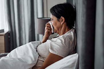 Image showing Sick, tissue and elderly woman in bed blowing nose, flu or viral infection in her home. Allergies, bacteria and senior female sneezing, coughing or sore throat in a bedroom with virus or covid