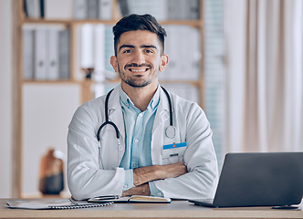 Image showing Happy, portrait and man doctor at desk in a healthcare, medical and hospital office. Smile, male professional and surgeon worker with arms crossed and computer feeling confident and pride in clinic