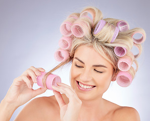 Image showing Hair care, curlers and young woman in a studio doing a natural, beautiful and curly hairstyle. Self care, happy and attractive female model with rollers for beauty isolated by a gray background.