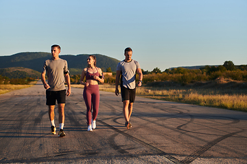 Image showing A group of young athletes running together in the early morning light of the sunrise, showcasing their collective energy, determination, and unity