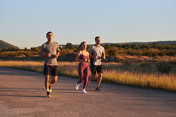 Image showing A group of young athletes running together in the early morning light of the sunrise, showcasing their collective energy, determination, and unity