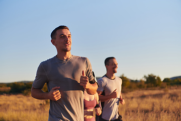 Image showing A group of young athletes running together in the early morning light of the sunrise, showcasing their collective energy, determination, and unity