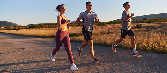 Image showing A group of young athletes running together in the early morning light of the sunrise, showcasing their collective energy, determination, and unity