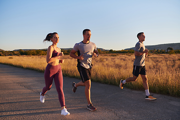 Image showing A group of young athletes running together in the early morning light of the sunrise, showcasing their collective energy, determination, and unity