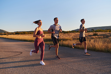 Image showing A group of young athletes running together in the early morning light of the sunrise, showcasing their collective energy, determination, and unity