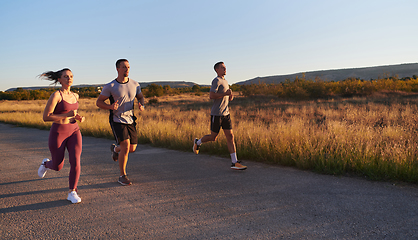 Image showing A group of young athletes running together in the early morning light of the sunrise, showcasing their collective energy, determination, and unity