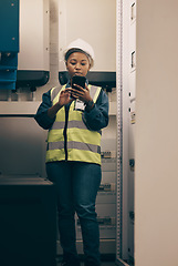 Image showing Black woman, engineering and electrician on cellphone in control room for system maintenance, industrial mechanic and inspection. Female technician, mobile technology and planning electrical services