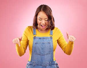 Image showing Excited, pointing and young woman in a studio for marketing, promotion or advertising. Shock, surprise and Asian female model with presentation or showing finger gesture isolated by a pink background