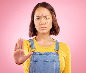 Image showing Woman, hand and stop in studio portrait with angry face, rejection or bad review by pink background. Gen z student girl, icon or emoji for protest, voice or opinion for feedback, activism or warning