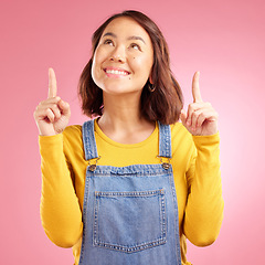 Image showing Happy, pointing and young woman in a studio for presentation for marketing, promotion or advertising. Smile, confident and Asian female model with showing finger gesture isolated by a pink background