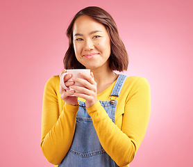 Image showing Woman, coffee and smile in studio portrait with hand holding hot drink for energy by pink background. Japanese student, gen z girl and happy for matcha, espresso or latte with fashion, relax and cup