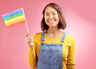 Image showing Woman, pride flag and studio portrait for smile, lgbtq goals and vote for love by pink background. Gen z student girl, gay icon or symbol for protest, voice or opinion for power, equality and rainbow