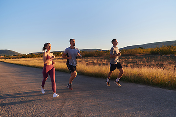 Image showing A group of young athletes running together in the early morning light of the sunrise, showcasing their collective energy, determination, and unity