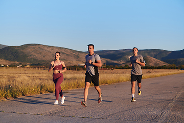 Image showing A group of young athletes running together in the early morning light of the sunrise, showcasing their collective energy, determination, and unity