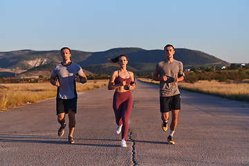 Image showing A group of young athletes running together in the early morning light of the sunrise, showcasing their collective energy, determination, and unity