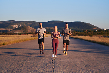 Image showing A group of young athletes running together in the early morning light of the sunrise, showcasing their collective energy, determination, and unity