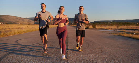 Image showing A group of young athletes running together in the early morning light of the sunrise, showcasing their collective energy, determination, and unity