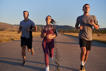 Image showing A group of young athletes running together in the early morning light of the sunrise, showcasing their collective energy, determination, and unity