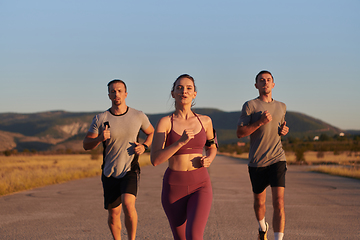 Image showing A group of young athletes running together in the early morning light of the sunrise, showcasing their collective energy, determination, and unity