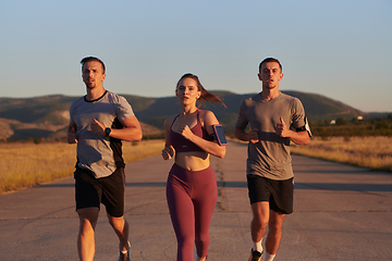 Image showing A group of young athletes running together in the early morning light of the sunrise, showcasing their collective energy, determination, and unity