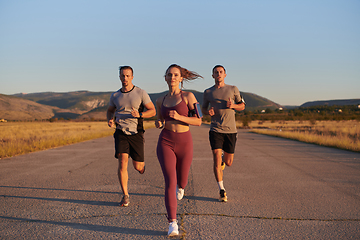 Image showing A group of young athletes running together in the early morning light of the sunrise, showcasing their collective energy, determination, and unity