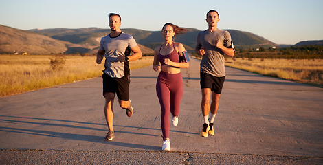 Image showing A group of young athletes running together in the early morning light of the sunrise, showcasing their collective energy, determination, and unity