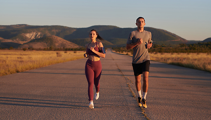 Image showing A handsome young couple running together during the early morning hours, with the mesmerizing sunrise casting a warm glow, symbolizing their shared love and vitality