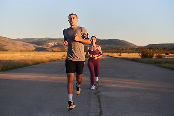 Image showing A handsome young couple running together during the early morning hours, with the mesmerizing sunrise casting a warm glow, symbolizing their shared love and vitality