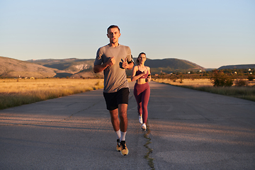 Image showing A handsome young couple running together during the early morning hours, with the mesmerizing sunrise casting a warm glow, symbolizing their shared love and vitality