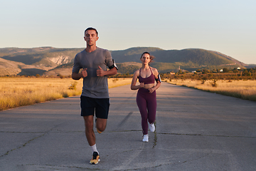 Image showing A handsome young couple running together during the early morning hours, with the mesmerizing sunrise casting a warm glow, symbolizing their shared love and vitality