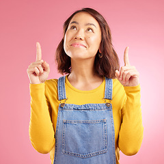 Image showing Smile, pointing and happy young woman in a studio for marketing, promotion or advertising. Happiness, confident and Asian female model with presentation finger gesture isolated by a pink background.